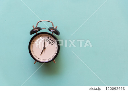 2025 and 2024 on black alarm clock on blue background, Merry Christmas  120092668