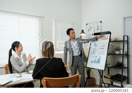 A man is standing in front of a white board and pointing at it 120095161
