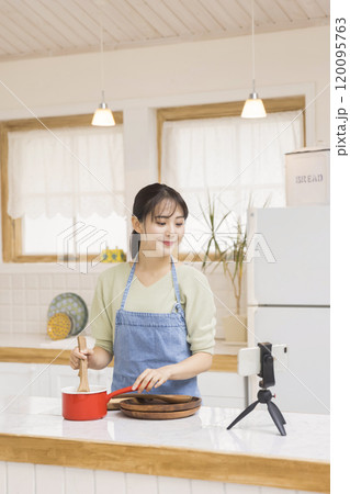 台所でスマホを見ながら料理をする若い主婦　料理イメージ 120095763