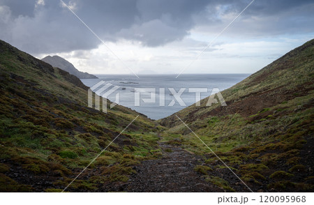 Islandic landscape with bay and ships with thick storm clouds above them, Madeira, Portugal 120095968