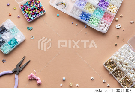 Crafting with colorful beads on a flat workspace with tools and containers in bright daylight 120096307