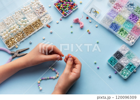 Creating colorful beaded jewelry with vibrant materials on a crafting table 120096309