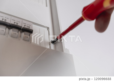 Close-up of a man unscrewing a screw with a screwdriver in an electric meter Close-up of a man unscrewing a screw with a screwdriver in an electric meter 120096688