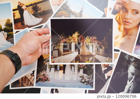Men's hands put on the table and show wedding photos. Men's hands put on the table and show wedding photos. 120096706