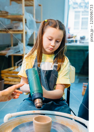 A teen girl sculpts from clay in a pottery workshop and dries with a fan. A teen girl sculpts from clay in a pottery workshop and dries with a fan. 120096733