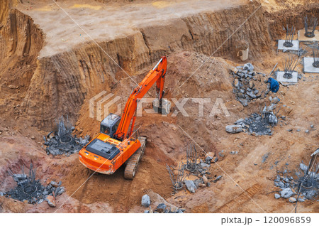 modern orange excavator digs the ground under the foundation pit at construction site modern orange excavator digs the ground under the foundation pit at construction site 120096859