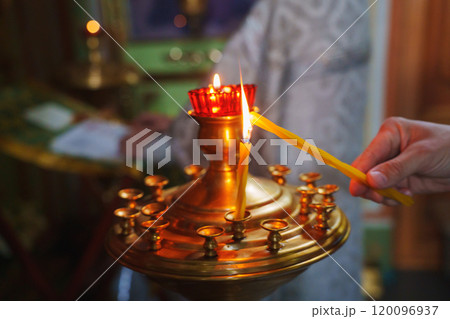 A gilded church candlestick with burning candles and an oil lamp. A gilded church candlestick with burning candles and an oil lamp. 120096937