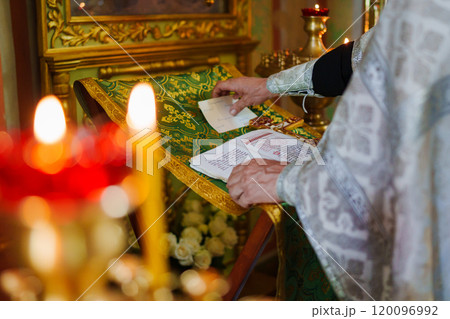 A priest with a prayer book on a table conducts the service.  120096992