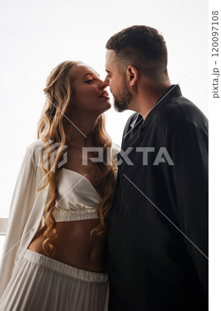 A gentle and romantic man and woman in silk pajamas on the windowsill A gentle and romantic man and woman in silk pajamas on the windowsill 120097108