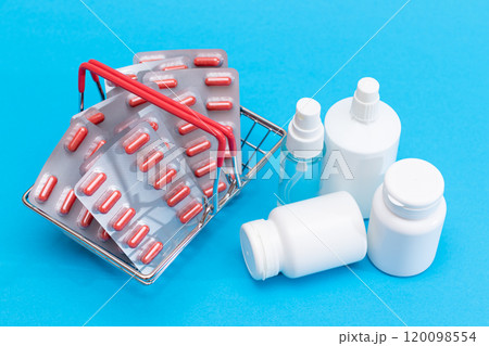 Pills and Capsules in Shopping Basket on Blue Background Pills and Capsules in Shopping Basket on Blue Background 120098554
