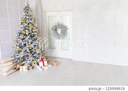 Snow-covered Christmas tree decorated with toys and gifts in the interior for the new year Snow-covered Christmas tree decorated with toys and gifts in the interior for the new year 120099819