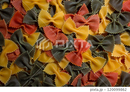 Dry Uncooked Colored Farfalle Pasta and Raw Macaroni on a Textured Background Dry Uncooked Colored Farfalle Pasta and Raw Macaroni on a Textured Background 120099862