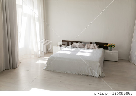 Bed by the window in the interior of a white bedroom Bed by the window in the interior of a white bedroom 120099866