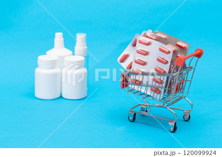 Pills and Capsules in Shopping Cart on Blue Background Pills and Capsules in Shopping Cart on Blue Background 120099924