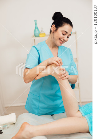 Chiropractor masseur giving foot massage to woman in spa 120100137