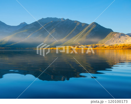 Mountain landscape at dawn. Sunbeams in a valley. Lake and high peaks in a mountain valley Mountain landscape at dawn. Sunbeams in a valley. Lake and high peaks in a mountain valley 120100173