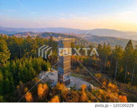 The wooden lookout tower at Cisarsky Kamen overlooks the vibrant autumn landscape near Liberec. The warm hues of sunset illuminate the surrounding forest, creating a serene atmosphere. The wooden lookout tower at Cisarsky Kamen overlooks the vibrant autumn landscape near Liberec. The warm hues of sunset illuminate the surrounding forest, creating a serene atmosphere. 120100229