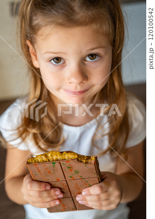 Dubai chocolate with pistachio paste and kataifi dough in hands of little girl. Confectionery handmade sweets at home in the kitchen.  120100542