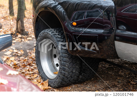 Close-up detail bottom pov view of dual twin offroad performance wheel of super heavy duty pickup truck car at autumn forest countryside driveway. Autumn weather woods offroad vehicle drive 120101746