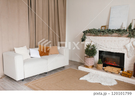 Living room with a white couch and a fireplace. Cozy apartment and warm atmosphere for Christmas 120101799