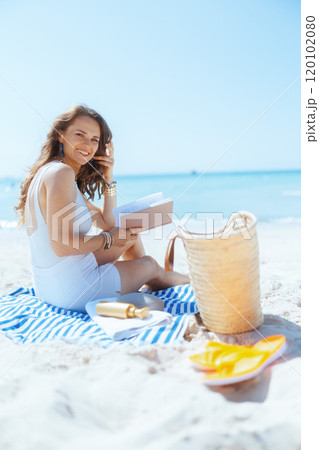 happy modern woman on seacoast with straw bag and book 120102080