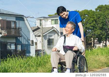街を歩く車椅子に乗ったシニア男性と介護士 街を歩く車椅子に乗ったシニア男性と介護士 120102593