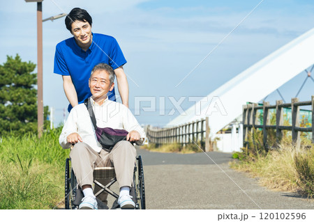 街を歩く車椅子に乗ったシニア男性と介護士 街を歩く車椅子に乗ったシニア男性と介護士 120102596