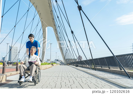 街を歩く車椅子に乗ったシニア男性と介護士 街を歩く車椅子に乗ったシニア男性と介護士 120102616