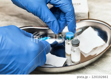 Gloved hand holding syringe preparing for vaccination Gloved hand holding syringe preparing for vaccination 120102661