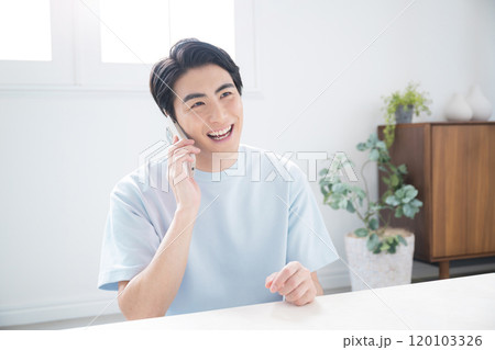 綺麗なリビングでスマホを持つ、通話する見上げるハンサムな男性 綺麗なリビングでスマホを持つ、通話する見上げるハンサムな男性 120103326