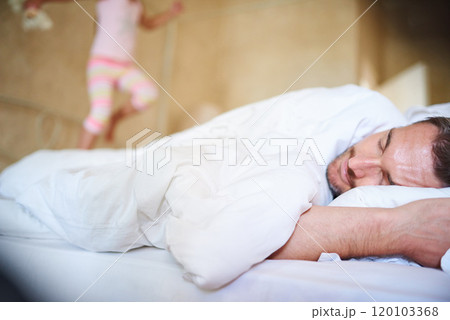 Its morning daddy. Shot of a sleeping dad with his little daughter jumping on the end of the bed. Its morning daddy. Shot of a sleeping dad with his little daughter jumping on the end of the bed. 120103368