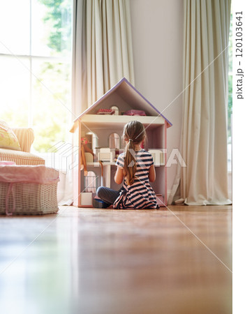 Giving her dolls a place to call home. Shot of a little girl playing with a dollhouse at home. 120103641