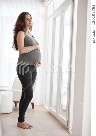 She cant wait to be a parent. Full length shot of a young pregnant woman standing in her home. She cant wait to be a parent. Full length shot of a young pregnant woman standing in her home. 120103763