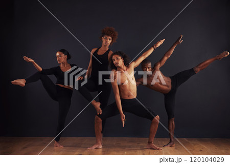 Powerful individuals. A group of dancers performing a dramatic pose in front of a dark background. 120104029