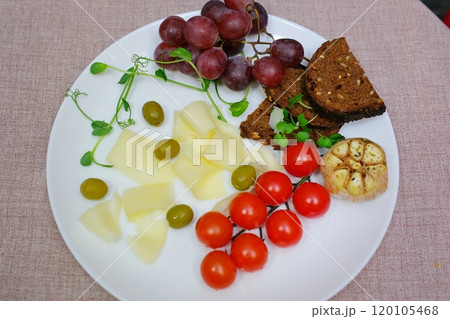 sprinkle black pepper cheese on white plate olives grapes cherry tomatoes delicious fresh cheese and sprouts of sprouted greens microgreens 120105468