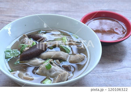 boiled slice pork stomuch and bone soup in bowl dipping spicy sauce cup on table  120106322
