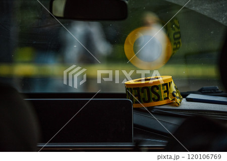 Roll of yellow Crime scene tape on dashboard of modern police car with reflection in windshield mirror, copy space Roll of yellow Crime scene tape on dashboard of modern police car with reflection in windshield mirror, copy space 120106769