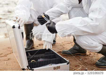 Close up of two scientists opening test kit while doing probes outdoors by water and holding test tubes, copy space 120106870