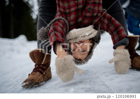 Girl is upside down, mother holding her by legs. Mom and girl enjoying winter holiday in the mountains. Girl is upside down, mother holding her by legs. Mom and girl enjoying winter holiday in the mountains. 120106991