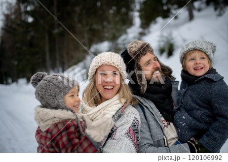 Young family is enjoying winter holiday in the mountains, standing in the middle of snowy forest. 120106992