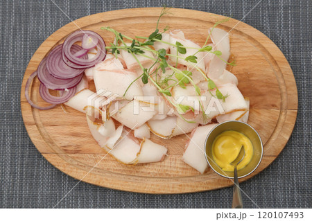 Slices of thinly sliced lard with onions and mustard. Lard with onions and mustard on a wooden board. 120107493