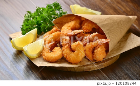 Crispy fried shrimp are served in a paper bag, garnished with parsley and lemon slices. 120108244