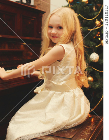 Portrait little girl child playing on piano at home near christmas tree 120110317