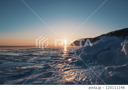 The sun sets over a frozen sea, casting a golden glow across the ice The sun sets over a frozen sea, casting a golden glow across the ice 120111146