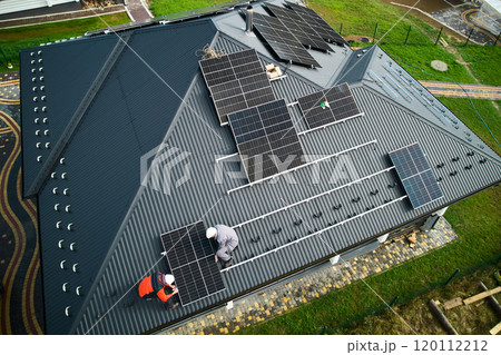 Builders building photovoltaic solar module station on roof of house. Men electricians in helmets installing solar panel system outdoors. Concept of alternative and renewable energy. Aerial view. Builders building photovoltaic solar module station on roof of house. Men electricians in helmets installing solar panel system outdoors. Concept of alternative and renewable energy. Aerial view. 120112212