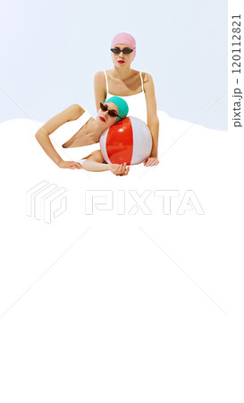 Two women wearing retro swim caps and sunglasses, posing with colorful beach ball on white background with blank space. 120112821