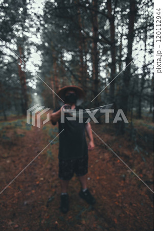 A masked man stands in a forest holding a katana. A samurai points a katana at the camera while standing in the forest. The image is blurry and mysterious, creating a sense of danger and intrigue. 120112944