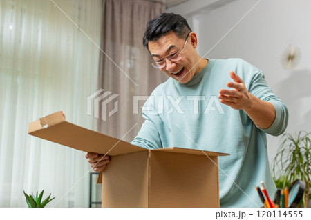Happy Chinese man shopper unpacking cardboard box delivery parcel online shopping purchase at home 120114555