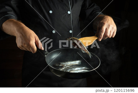 A skilled chef expertly flips fresh fish in a hot skillet, showcasing culinary techniques in a stylish kitchen. The steam and action create a vibrant cooking atmosphere A skilled chef expertly flips fresh fish in a hot skillet, showcasing culinary techniques in a stylish kitchen. The steam and action create a vibrant cooking atmosphere 120115696
