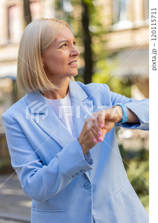 Serious sad mature businesswoman standing outdoors looking around waiting for business meeting Serious sad mature businesswoman standing outdoors looking around waiting for business meeting 120115711